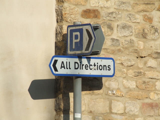 Road sign with arrow toward parking and one towards "all directions"
